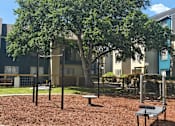 Thumbnail 11 of 33 - a playground with a tree in front of an apartment building