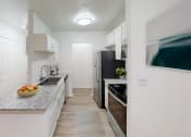 Thumbnail 3 of 23 - a kitchen with white cabinets and a counter top with a bowl of fruit