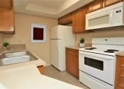 Thumbnail 4 of 8 - a kitchen with white appliances and wooden cabinets and a sink