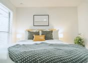 Thumbnail 6 of 37 - a bedroom with a bed with a gray blanket and pillows