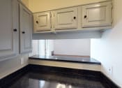 Thumbnail 9 of 43 - a kitchen with white cabinets and black counter top and a window