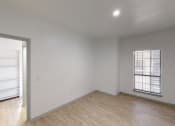 Thumbnail 25 of 43 - a bedroom with white walls and wood flooring and an open door to a closet