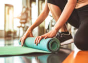 Thumbnail 36 of 39 - a woman rolling up a yoga mat in a gym