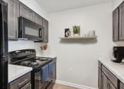 Thumbnail 13 of 19 - a kitchen with black appliances and white counter tops and a black stove and microwave