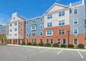 Thumbnail 19 of 19 - a brick apartment building with blue siding and a parking lot