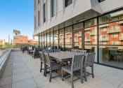 Thumbnail 4 of 26 - a patio with tables and chairs on the side of a building