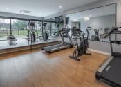 Thumbnail 12 of 28 - a gym with treadmills and other exercise equipment on a wooden floor