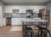 Thumbnail 2 of 28 - a kitchen with white cabinets and a table with black stools