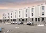 Thumbnail 7 of 28 - a large white building with cars in a parking lot