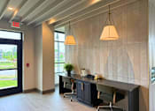 Thumbnail 8 of 31 - A modern office space with a desk, chairs, and a hanging light fixture.