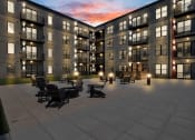 Thumbnail 5 of 16 - an exterior view of an apartment building at dusk with tables and chairs