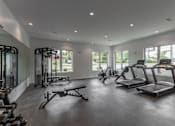 Thumbnail 6 of 23 - A spacious gym with treadmills, elliptical machines, and other exercise equipment.