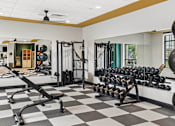 Thumbnail 9 of 31 - A gym with a variety of equipment including weights and a squat rack.