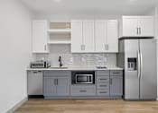 Thumbnail 28 of 31 - A kitchen with a refrigerator, microwave, and sink.