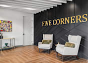 Thumbnail 4 of 31 - Two white chairs are placed in front of a black wall with the words "FIVE CORNERS" written on it.