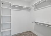 Thumbnail 26 of 31 - A white closet with shelves and a carpeted floor.