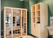 Thumbnail 11 of 31 - A wooden cabinet with glass doors and shelves is next to a sink in a room.