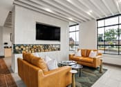 Thumbnail 5 of 31 - A living room with a tan couch and a flat screen TV mounted on the wall.