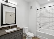 Thumbnail 25 of 31 - A bathroom with a white toilet, a sink, and a bathtub.