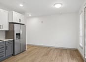 Thumbnail 30 of 31 - A kitchen with a refrigerator, cabinets, and a wooden floor.