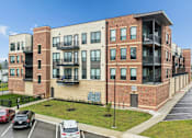 Thumbnail 3 of 31 - A multi-story apartment building with a parking lot in front.