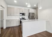 Thumbnail 16 of 26 - A modern kitchen with wooden floors and white appliances.