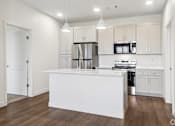 Thumbnail 20 of 26 - A white kitchen with wooden floors and white cabinets.