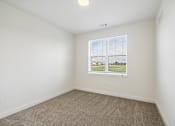 Thumbnail 24 of 26 - A room with a window showing a view of a grassy area.