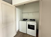 Thumbnail 27 of 31 - Two white front loading washing machines in a laundry room.