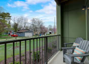 Thumbnail 14 of 30 - a balcony with two chairs and a view of a yard and houses