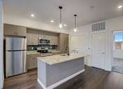 Thumbnail 18 of 30 - A modern kitchen with a stainless steel refrigerator and a marble countertop.