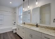 Thumbnail 23 of 30 - A bathroom with a marble countertop and a large mirror.
