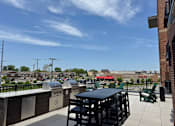 Thumbnail 17 of 31 - A rooftop patio with a black table and chairs.