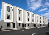 Thumbnail 6 of 28 - a row of white apartment buildings with a street in front of them