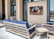 Thumbnail 12 of 26 - A wooden bench with a blue cushion sits on a patio.