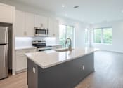 Thumbnail 17 of 23 - A modern kitchen with a large island and stainless steel appliances.