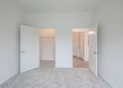 Thumbnail 15 of 23 - A white room with two doors and a carpeted floor.