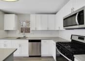 Thumbnail 2 of 35 - a kitchen with white cabinets and a stove and a microwave