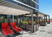 Thumbnail 8 of 22 - a patio with red chairs and potted plants in front of a building