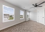 Thumbnail 46 of 48 - A room with a ceiling fan and two windows showing a view of a house.