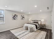Thumbnail 4 of 16 - Blue Springs, MO Townhomes - Chapman Ridge Townhomes - A Bedroom With Queen-Sized Bed, Abstract Wall Art, Vinyl Plank Flooring, Matching Bedside Lamps, And A Large Window.