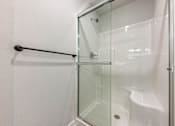 Thumbnail 44 of 48 - A white shower stall with a glass door and a black grab bar.