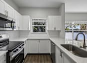 Thumbnail 12 of 61 - A kitchen with white cabinets and a black countertop.