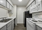 Thumbnail 1 of 21 - A kitchen with black and white appliances and a marble counter.