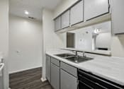 Thumbnail 3 of 21 - A kitchen with a sink and a stove top oven.