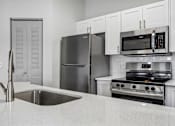 Thumbnail 14 of 61 - A modern kitchen with a stainless steel refrigerator, microwave, and oven.