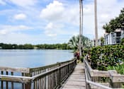 Thumbnail 22 of 22 - A wooden walkway leads to a body of water with a house on the right.