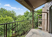Thumbnail 14 of 21 - A balcony with a metal railing overlooks a wooded area.