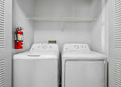 Thumbnail 16 of 61 - Two white washing machines in a small laundry room.