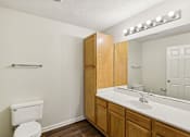 Thumbnail 22 of 58 - A white toilet sits in a bathroom with wooden cabinets and a mirror.